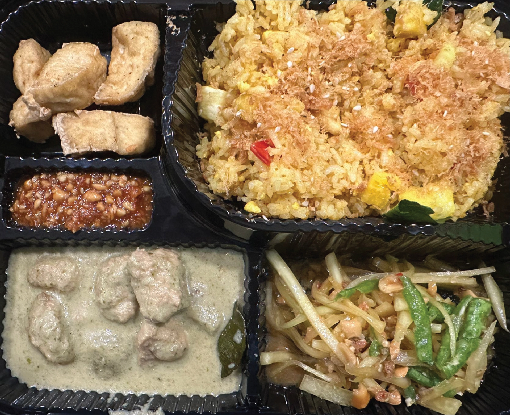 A black bento box featuring Thai dishes, ideal for the best food catering to Singapore.